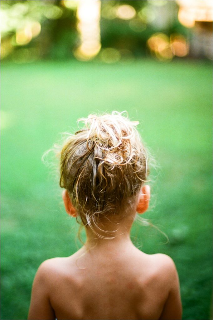 child with messy bun outside during summer