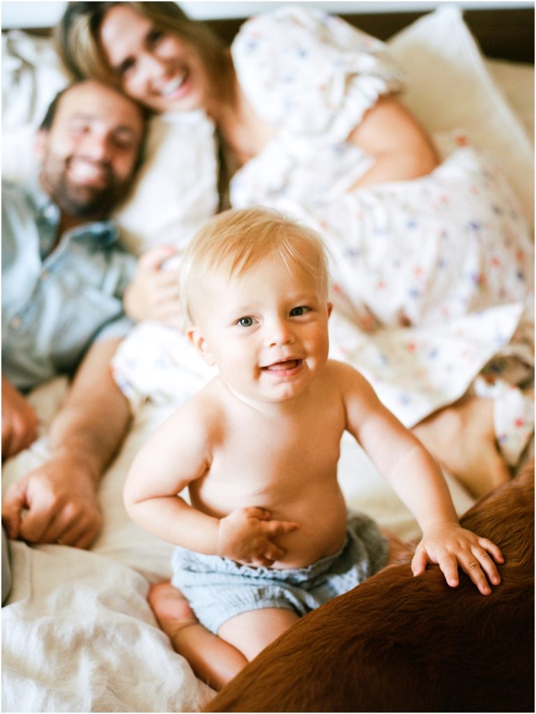 baby smiling at camera with mom and dad in the background